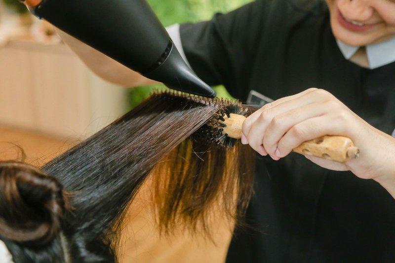 ドライヤーとブラシでロングヘアを仕上げる様子